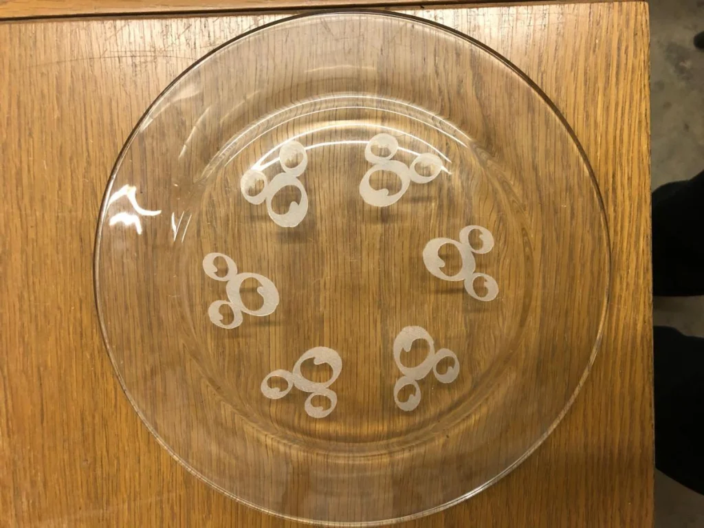 Clear glass plate with abstract design, wooden table.