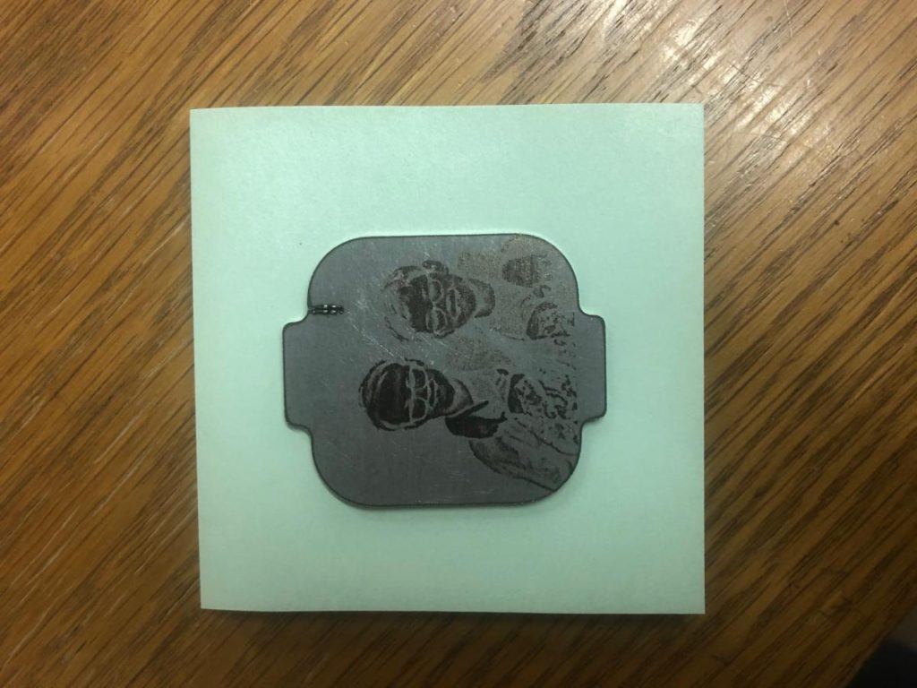Metal engraving of two people on wood surface.