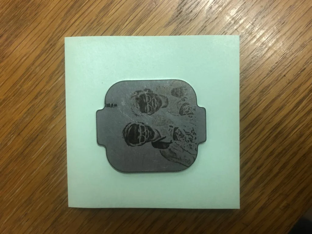 Metal engraving of two people on wood surface.
